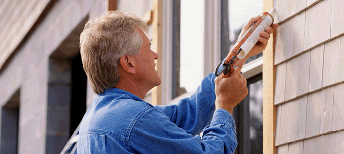 Gentleman working on siding of a house image